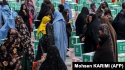 Afghan women gather around aid parcels that they received from the King Salman Humanitarian Aid and Relief Center in Herat in June.
