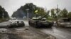 Украинский танк проезжает мимо бывшего российского контрольно-пропускного пункта в городе Изюм Харьковской области, ранее освобожденного Вооруженными силами Украины от российской армии, 16 сентября 2022 года