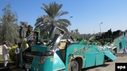 FILE: Pakistani security officials inspect the wreckage of a passenger bus at the scene of an accident in Khairpur district of southern Sindh province in 2014.